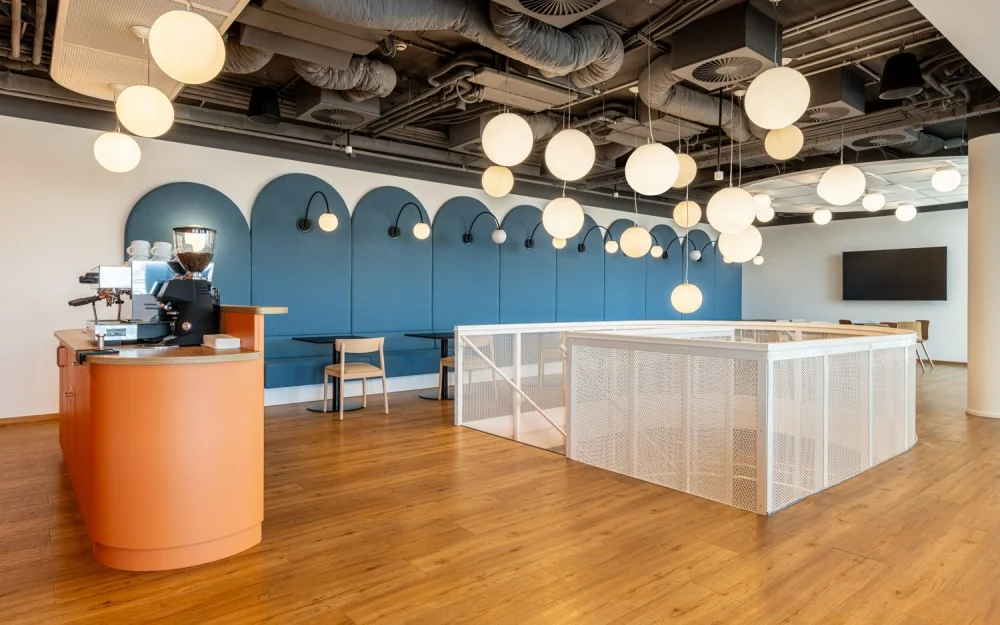 Open lounge around the staircase with a café counter, built-in seating and hanging lights